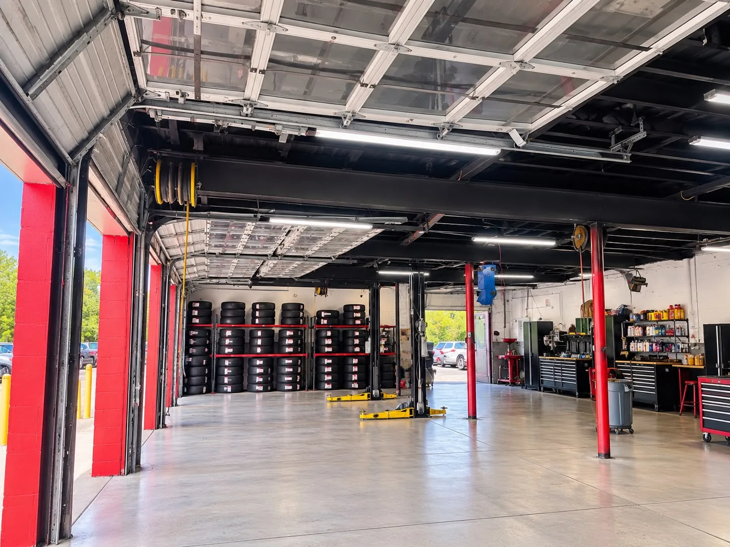 KC Bros with the bay doors rolled up: red door frames, two lifts, tire racks along the back wall and toolboxes on the right